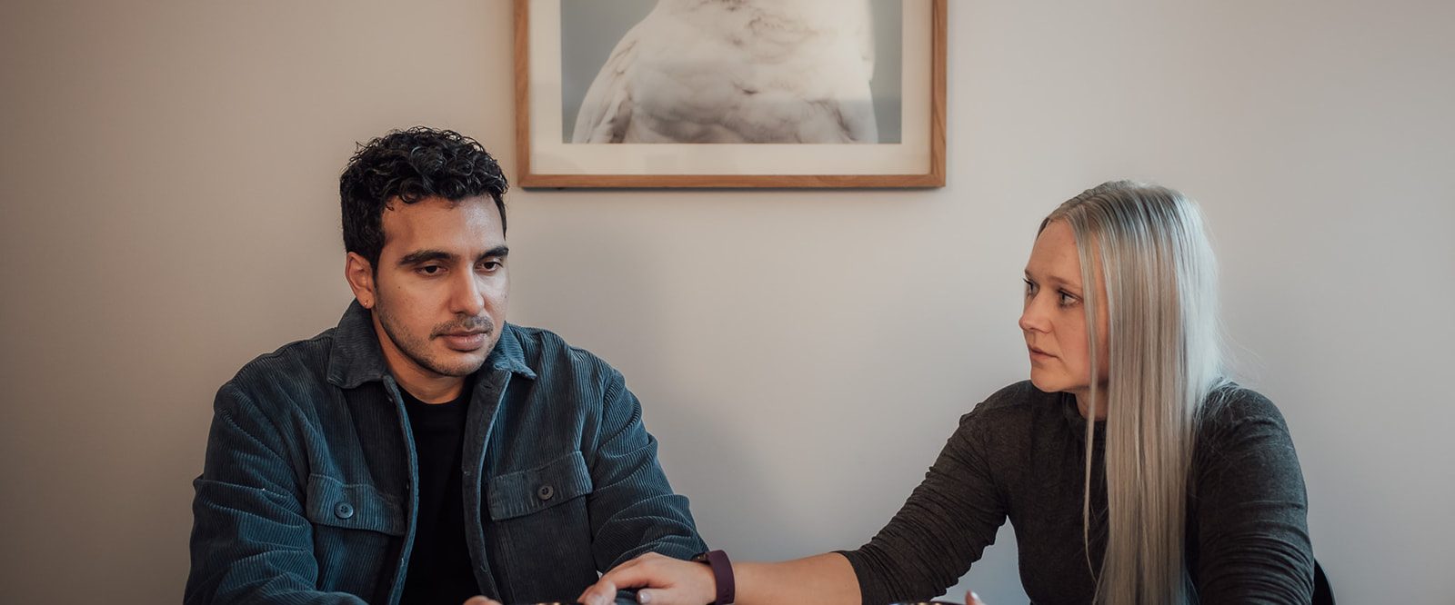A man and woman sitting at a table, drinking tea and having a serious conversation.