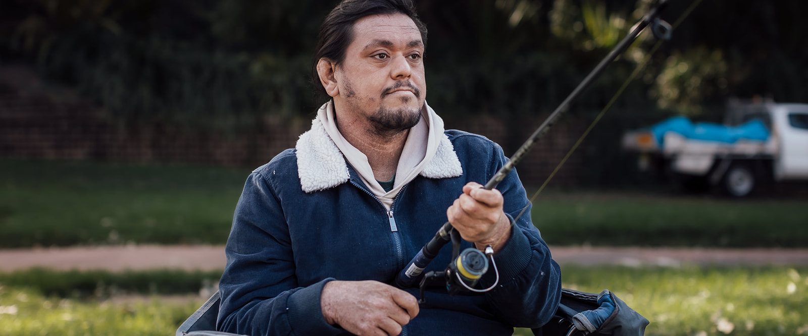 A man sitting in a chair fishing.